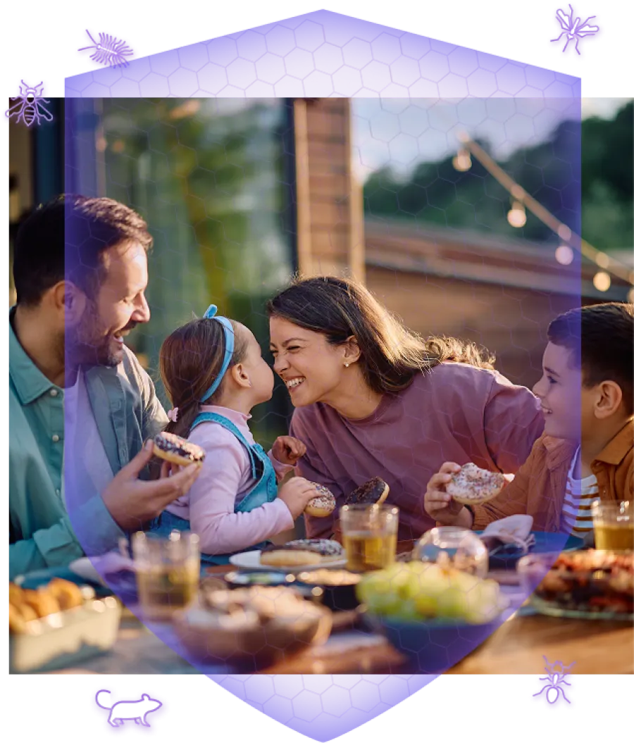 Family enjoying outdoor meal with donuts and drinks, sharing joyful moments at a sunlit table.
