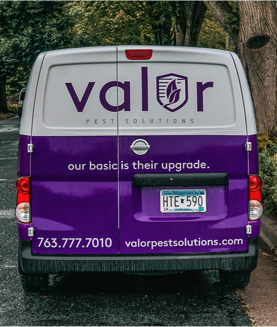 Rear view of a Valor Pest Solutions van with company branding, contact info, and Minnesota license plate.
