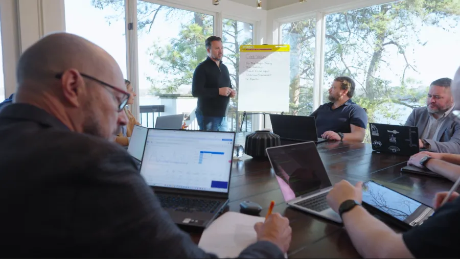 a group of men sitting at a table with laptops
