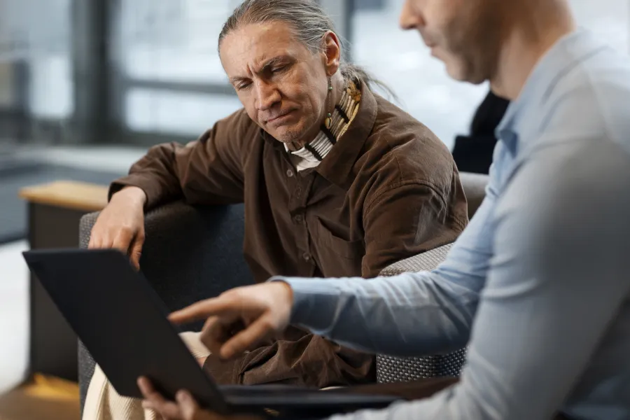 a person showing a laptop to another man