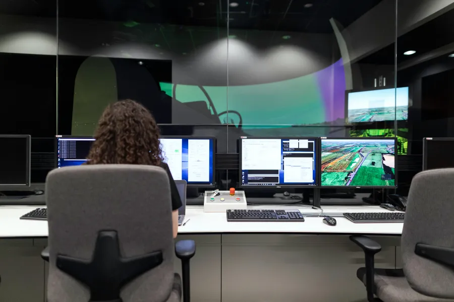 a person sitting at a desk with several monitors