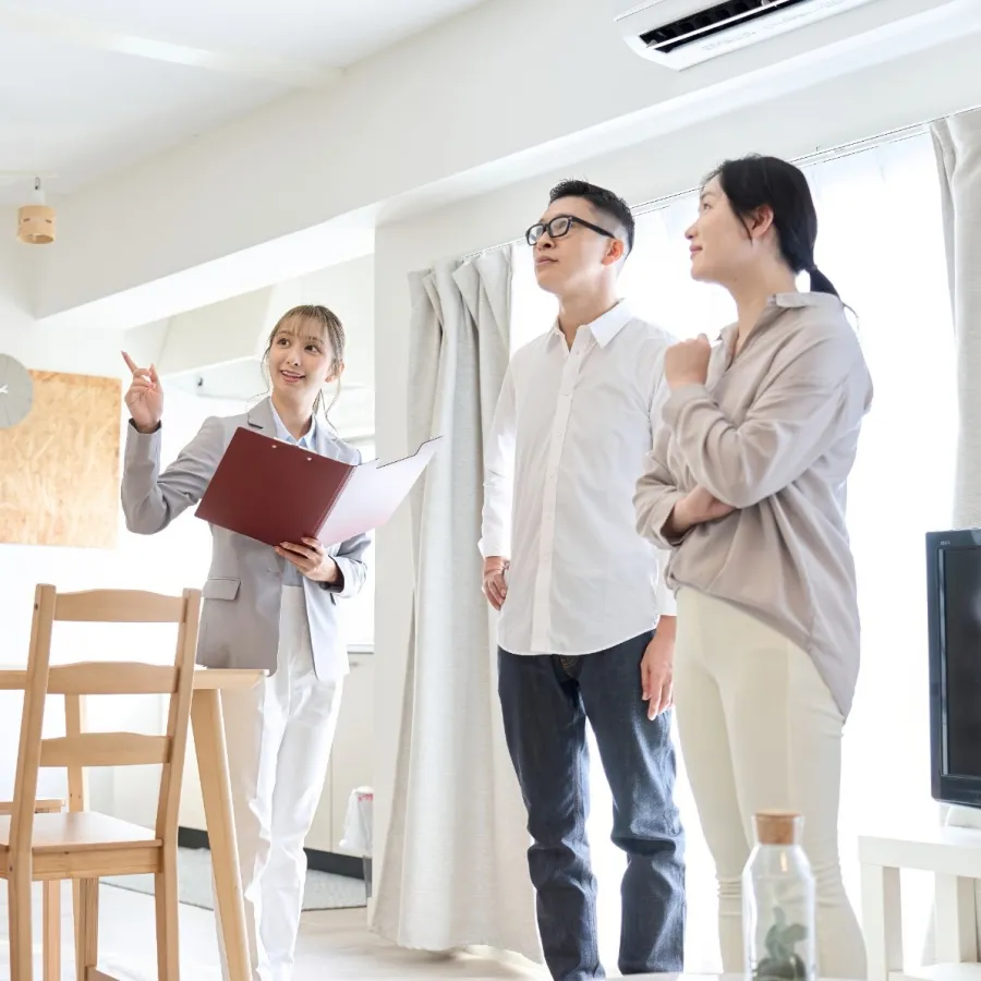 Real estate agent showing a young couple a bright modern apartment during a home tour.