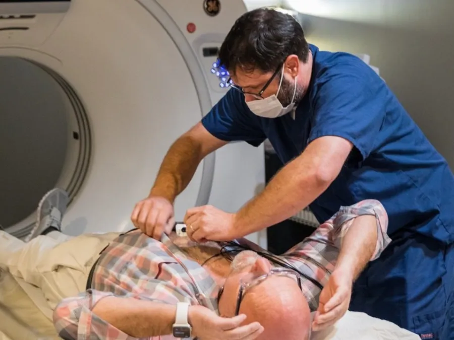A medical technician prepares a patient for a CT scan in a clinical setting.