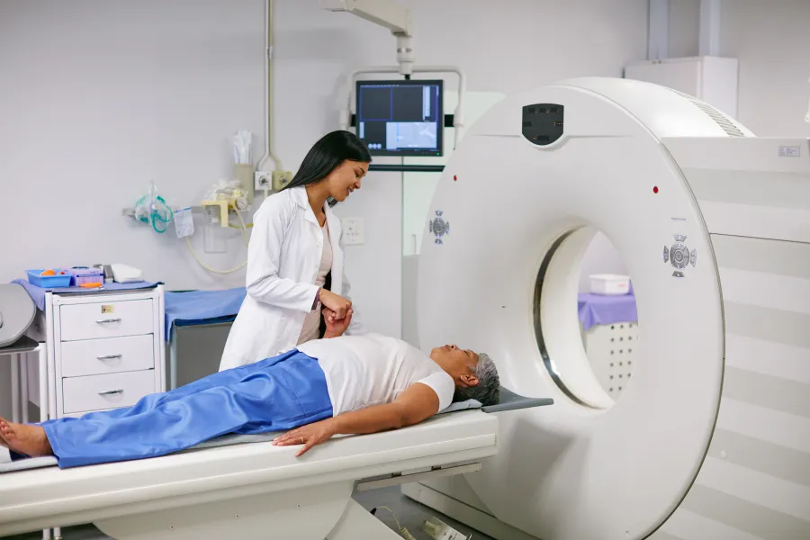 A healthcare professional assists a patient during a CT scan procedure in a medical facility.