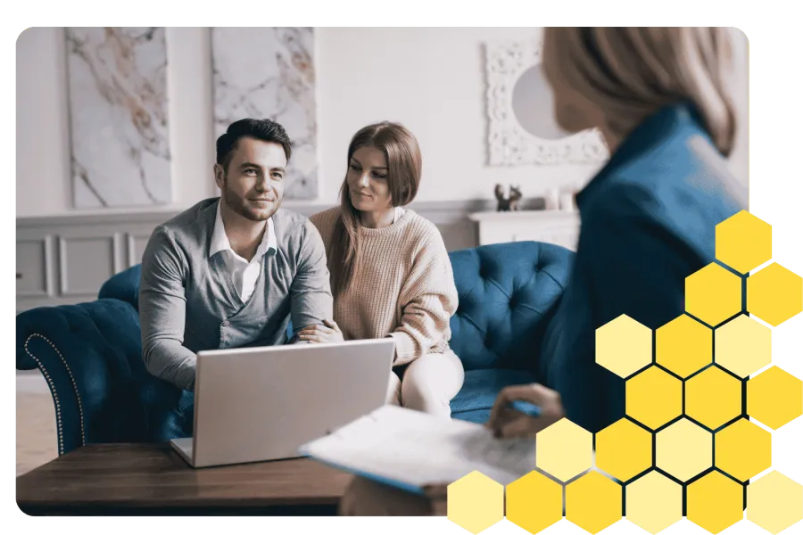 Young couple discussing plans with professional advisor sitting on a blue couch with laptop and documents.