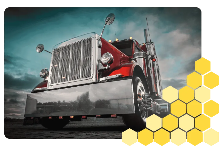 Low-angle view of a shiny red semi truck with prominent chrome grill and mirrors under a cloudy sky.