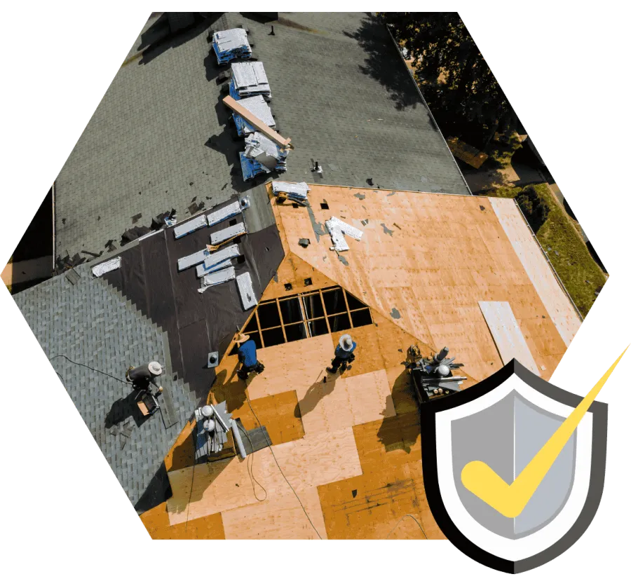 Aerial view of workers installing roofing materials on a house with both shingled and plywood sections visible.