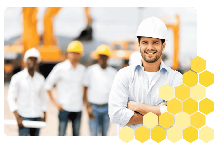 Confident construction engineer in white helmet smiling with teammates and heavy machinery in background
