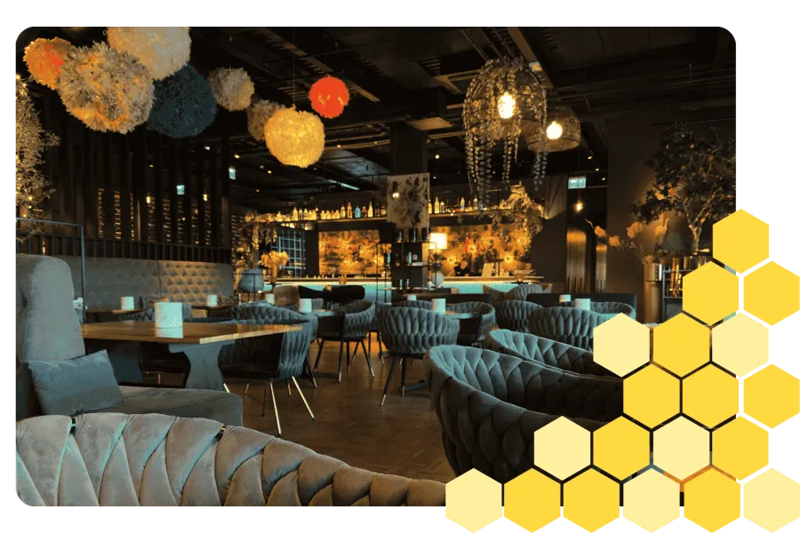 Cozy modern restaurant interior with velvet seating, wooden tables, and colorful hanging light fixtures.