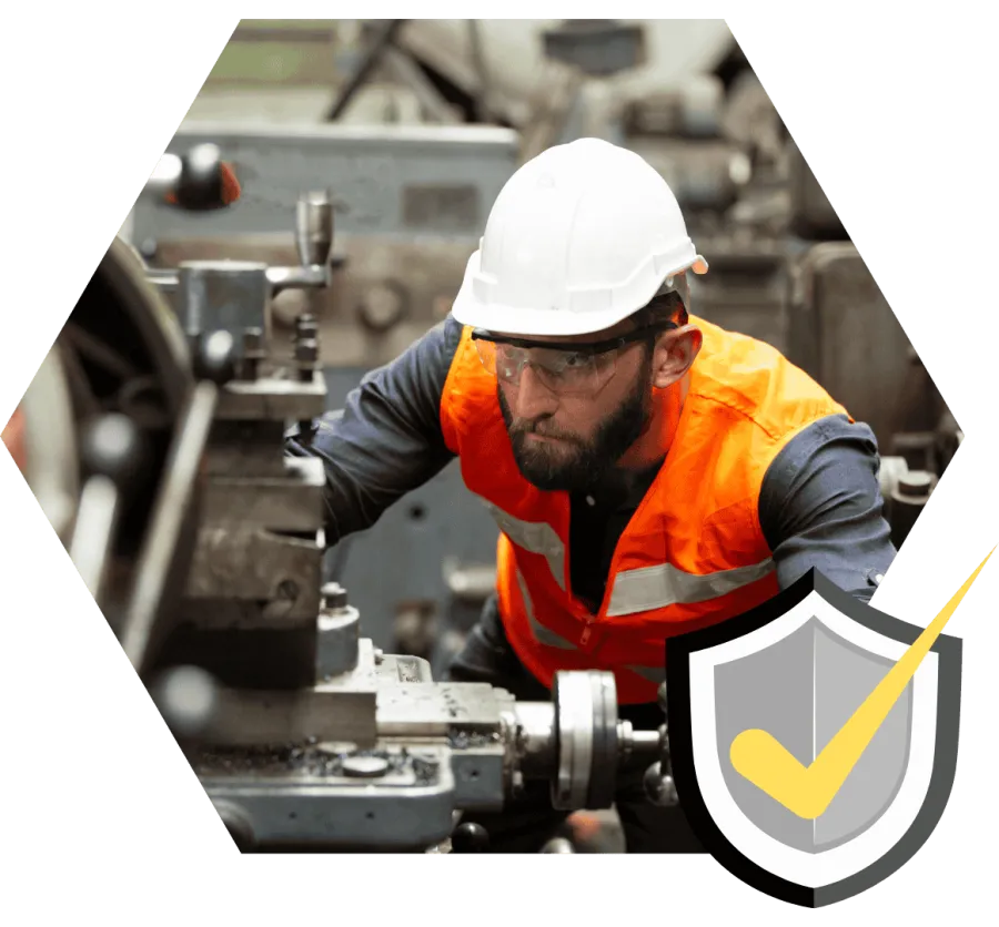 Engineer wearing safety gear operates industrial machinery focused on manual precision work indoors.