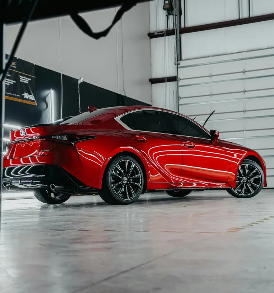 Red Lexus IS 250 sports sedan parked indoors with glossy finish and black alloy wheels.