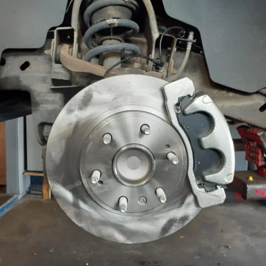 Close-up of a car's brake disc and caliper assembly during maintenance or repair in a garage setting