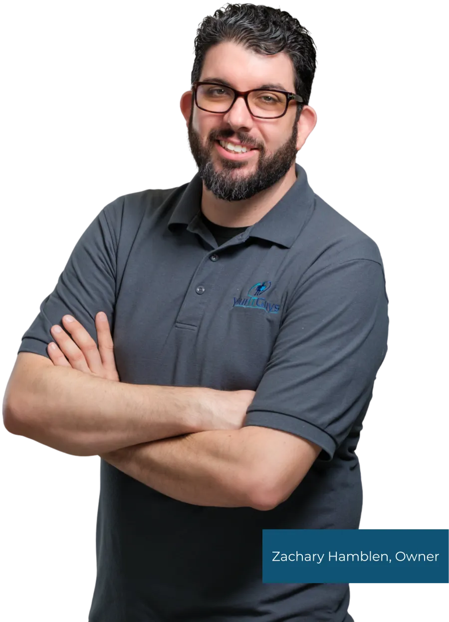 Smiling man with glasses and beard wearing a gray polo shirt with YouthGuys logo, arms crossed.